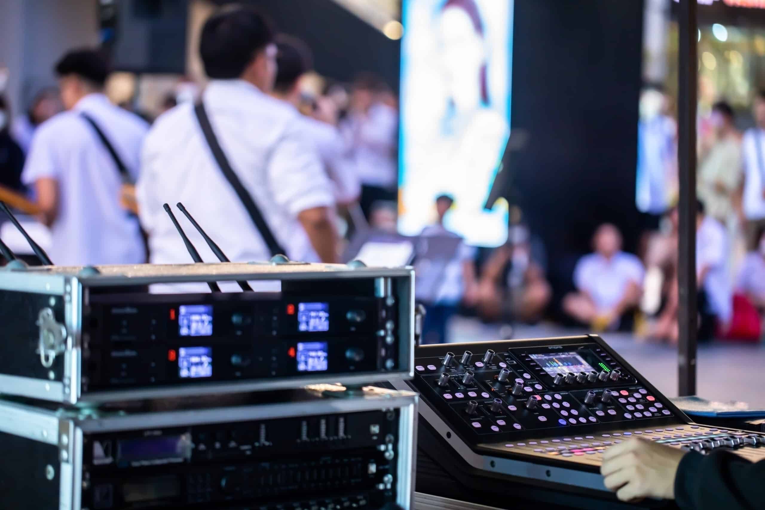 Selective focus to smart sound mixer board with blurry musician in concert event. Music on street.